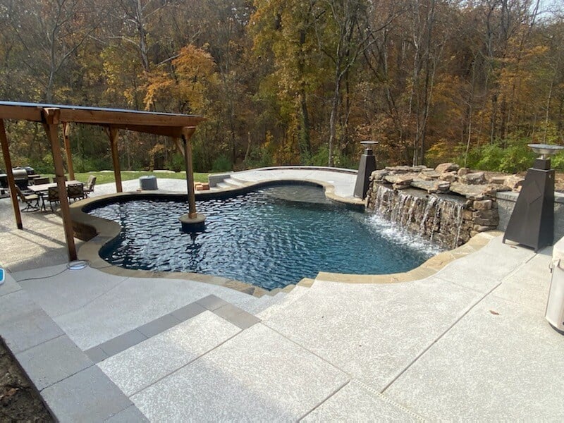 freeform, gunite pool with rock wall and pergola